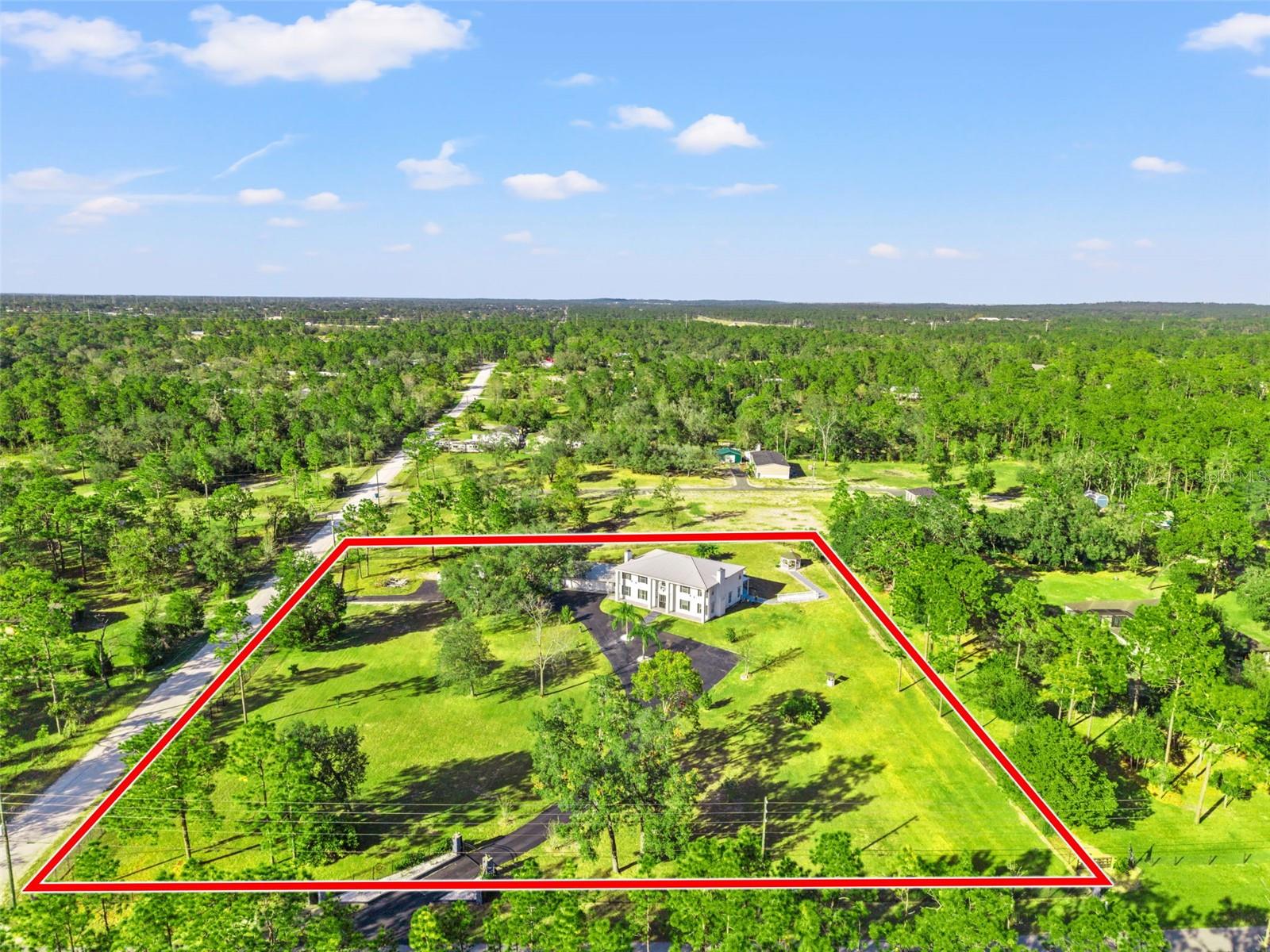 Aerial photo of this Colonial-inspired estate, designed with the grandeur reminiscent of the iconic “White House.” Set on a private 2.40-acre property and property lines.