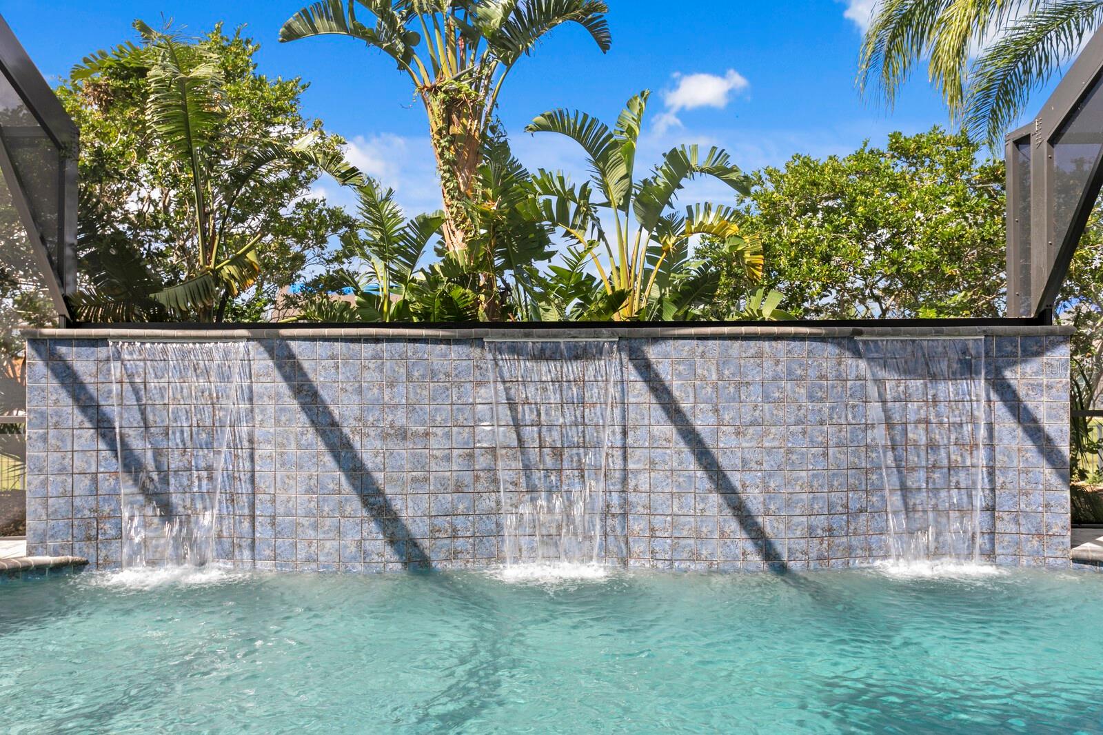 The heated saltwater pool features a custom triple waterfall design and provides resort-like privacy