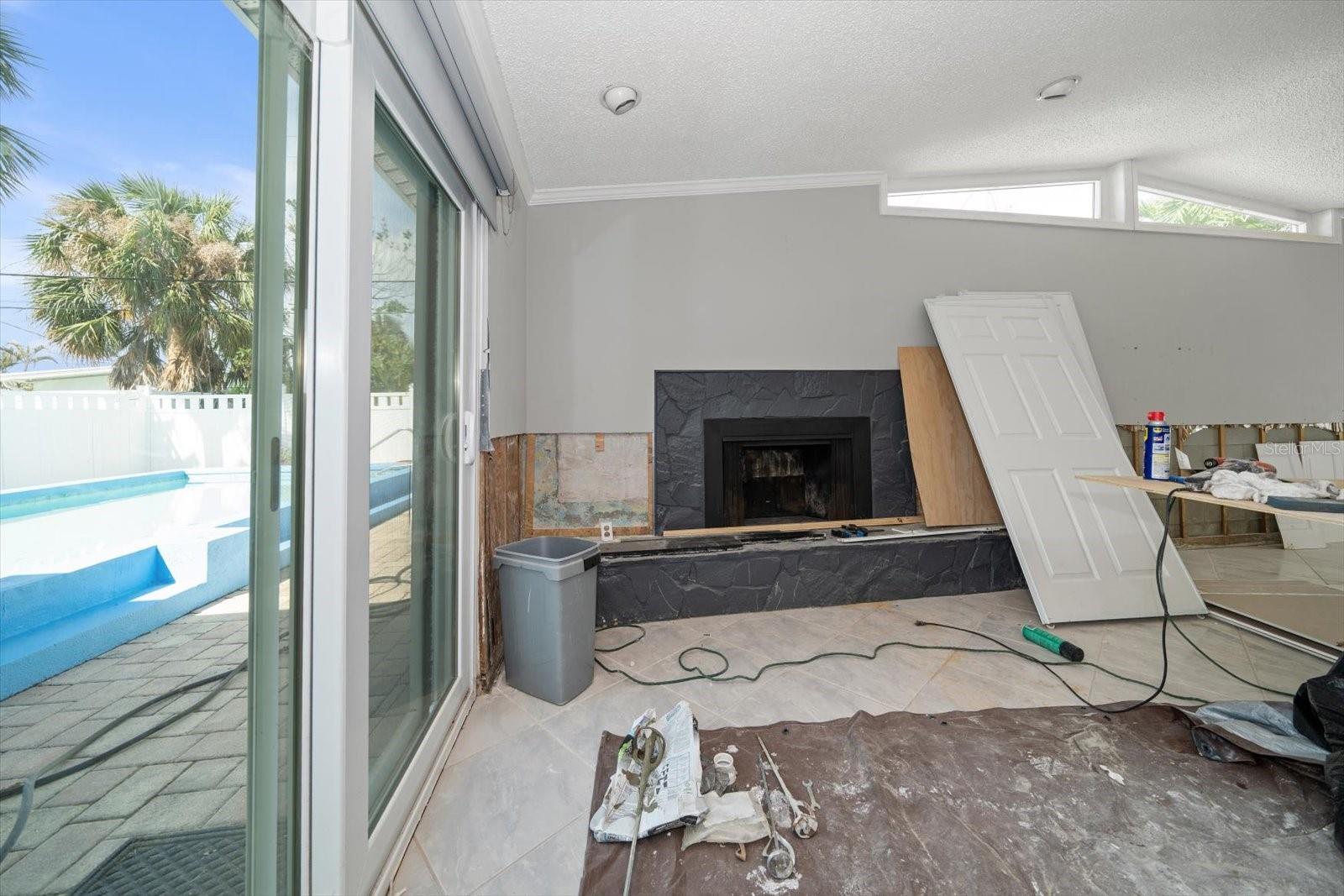 Great room with vaulted ceiling, fireplace, hurricane rated sliders and high end designer vertical blinds. Drywall to be installed, textured and painted