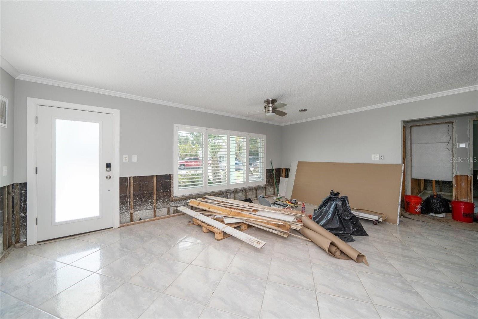 Living Room with new tile, Impact windows and Plantation Shutters. Drywall to be installed, textured and painted.