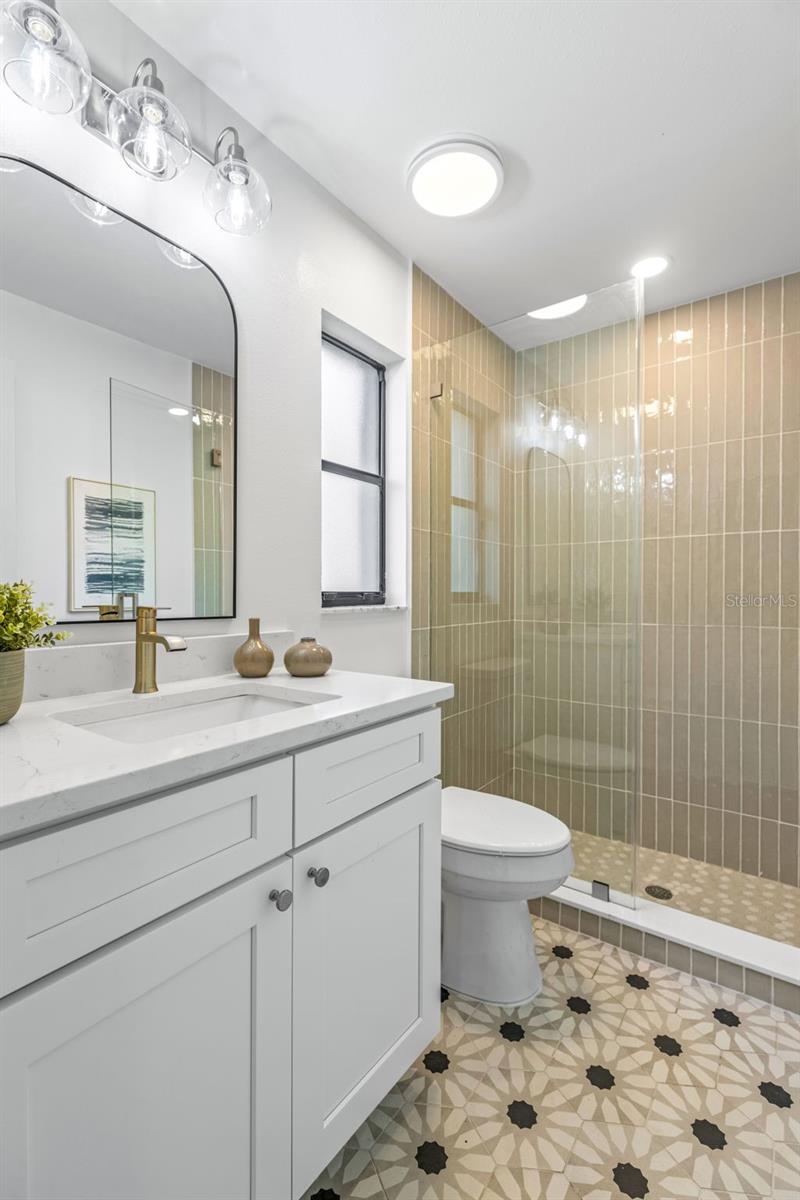 Primary bathroom with mosaic tile and seamless glass shower