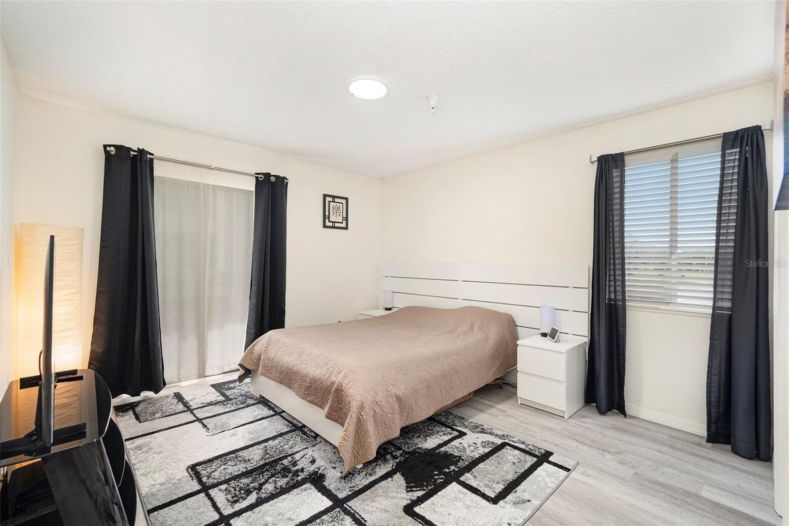 The spacious bedroom features a large walk-in closet and a sliding glass door to the balcony, offering stunning lake views.