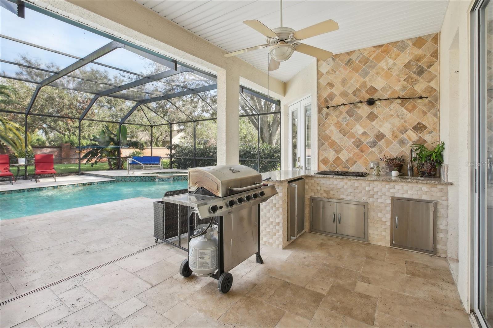 A fully equipped outdoor kitchen is complete with s beverage fridge, gase griddle and sink.