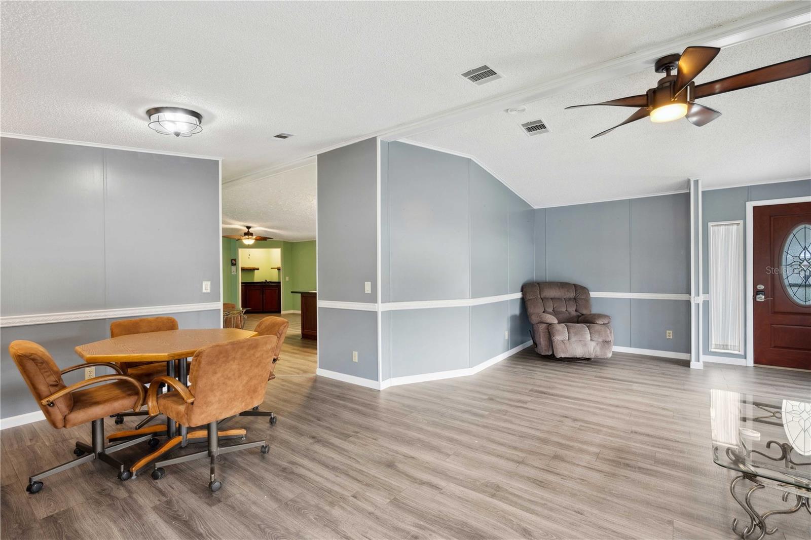 Large open living room with updated flooring, ceiling fan, and double pane windows.