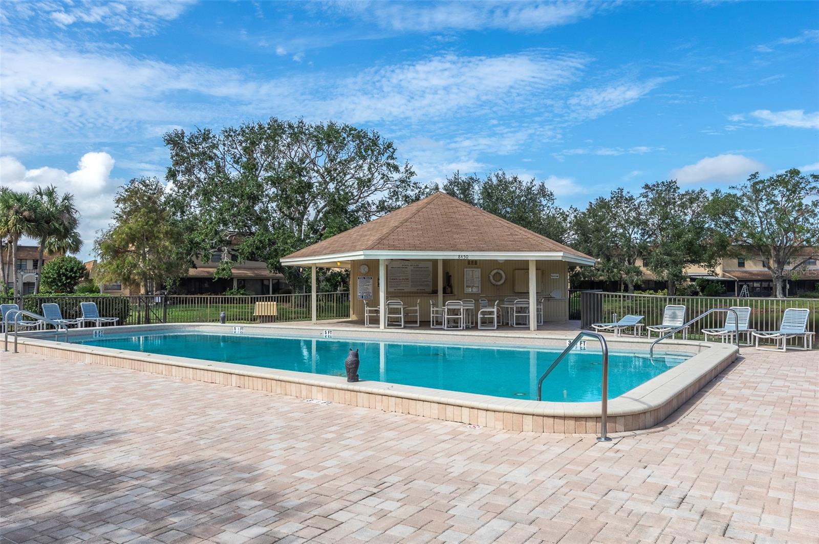 POOL AREA WITH SHADE COVERED CHAIRS AND TABLES TO ENJOY