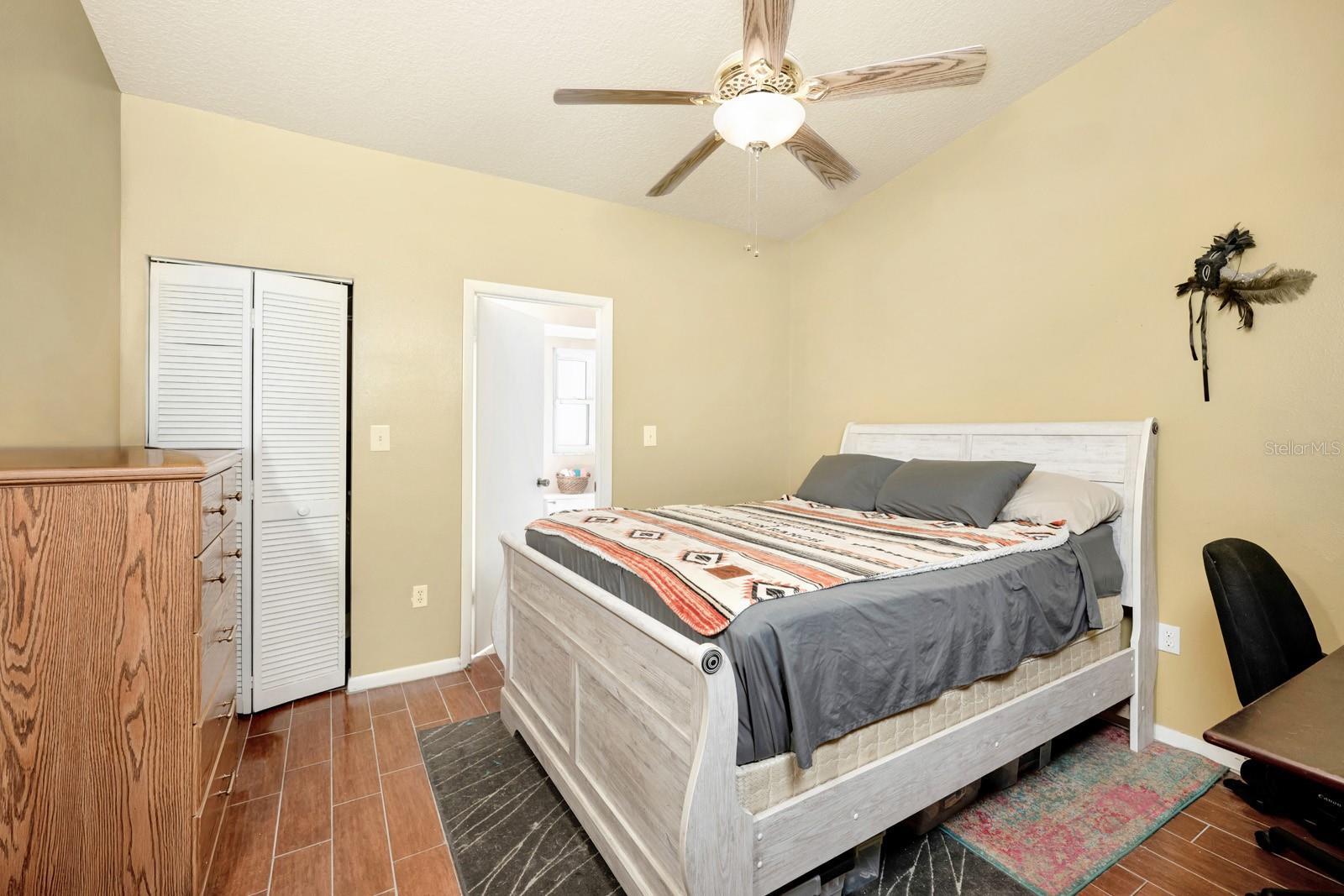 Primary Bedroom with a Vaulted Ceiling, Ceramic Tile Plank Flooring, Walk-in Closet, and Ensuite Bathroom.