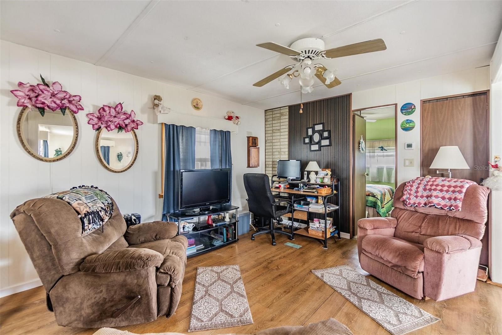 Living room has ceiling fan and laminate flooring.