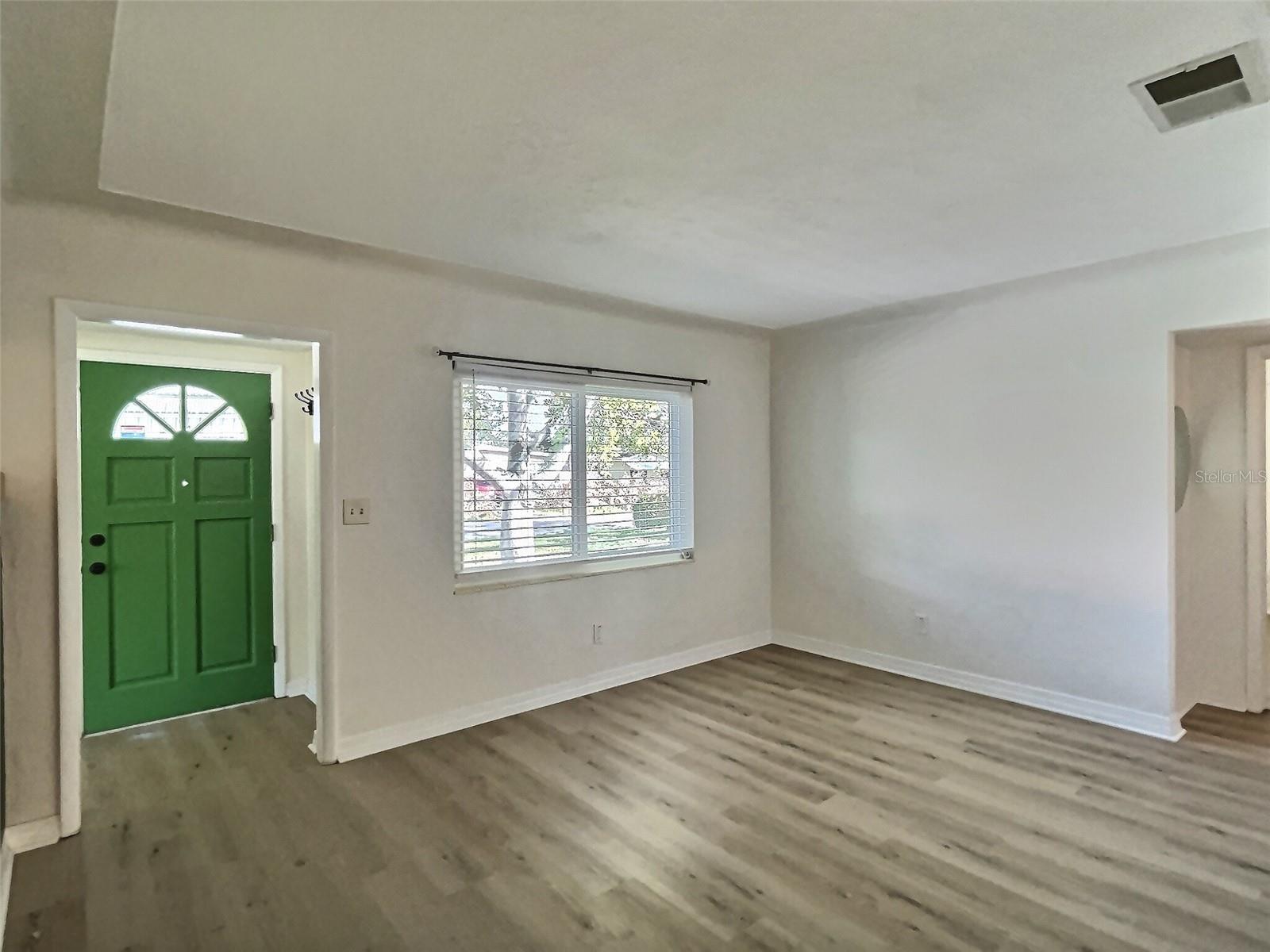 Spacious living room looking toward the cheery green front door. Cove ceilings & brand new luxury vinyl floors.