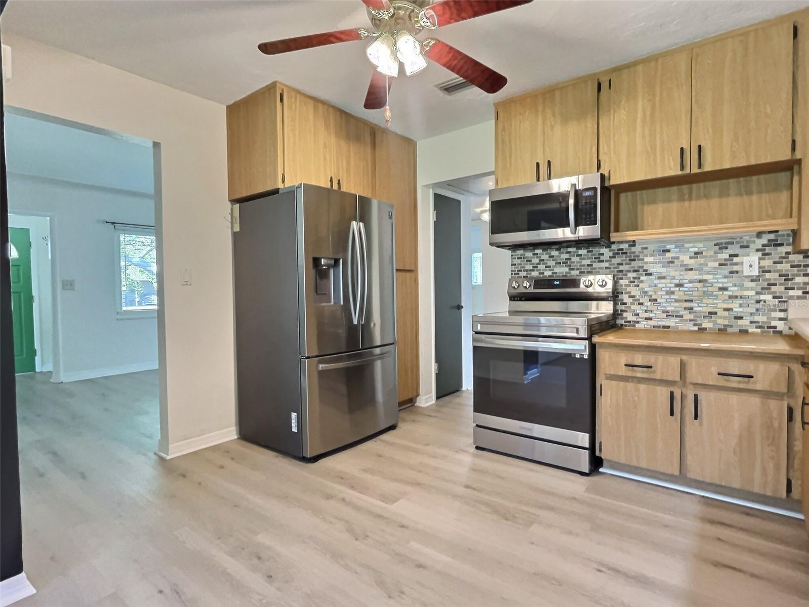 Kitchen with 2022 range, refrigerator, & microwave.