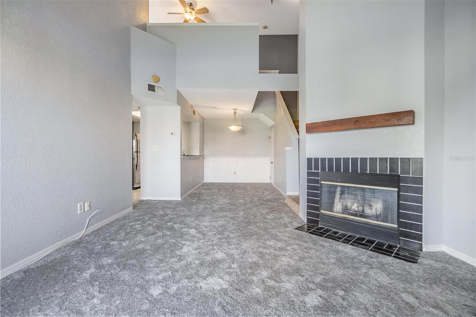 From front door looking toward dining room, loft, and living room with high open ceiling featuring a cozy fireplace and sliders out to the second floor balcony.