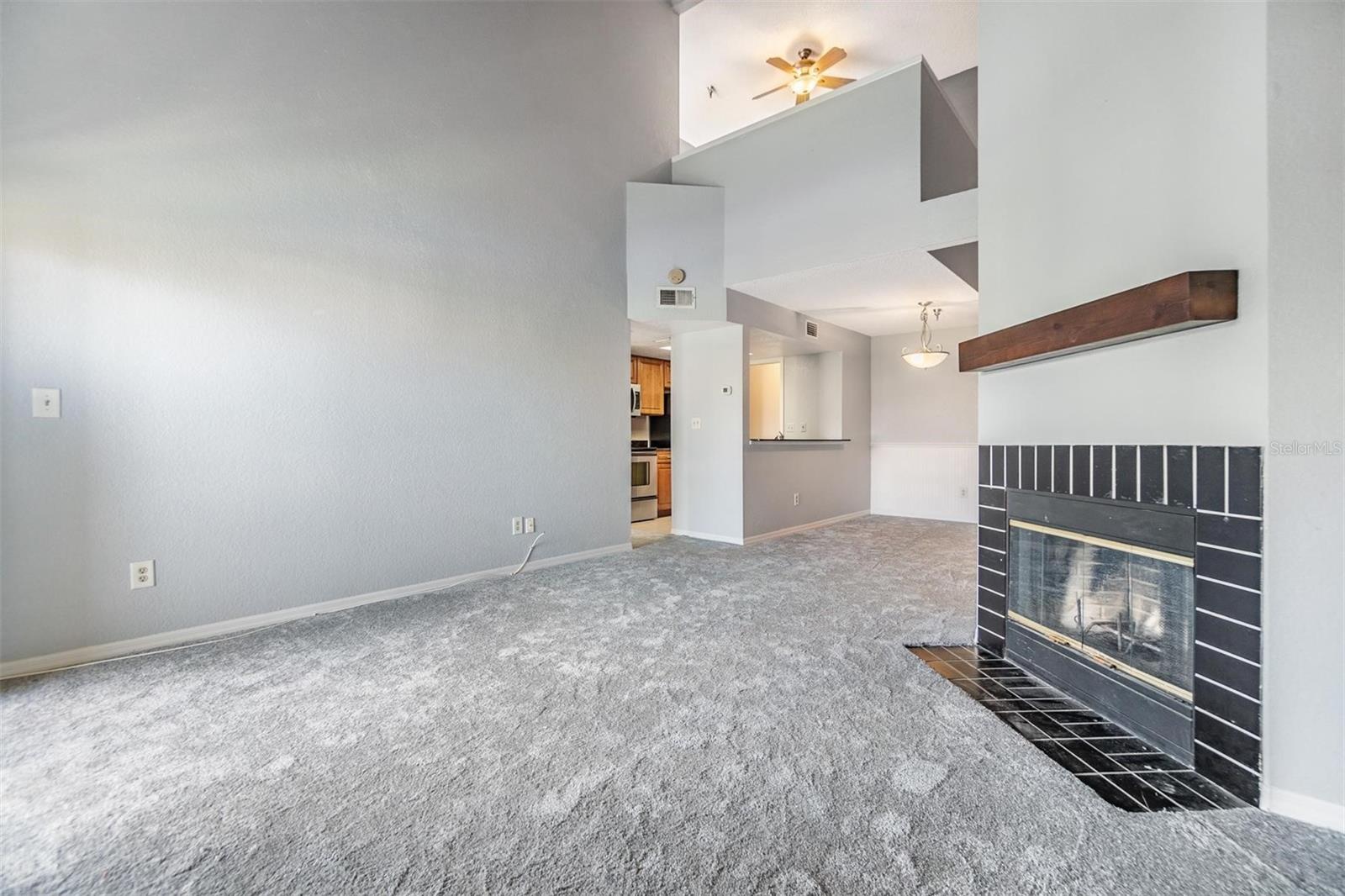 Living room with high open ceiling featuring a cozy fireplace and sliders out to the second floor balcony.