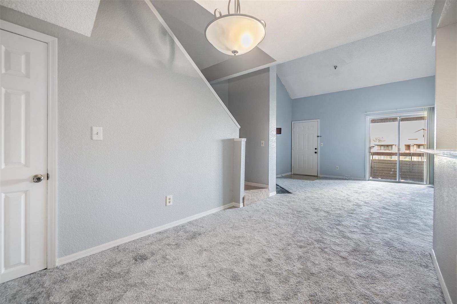 Living room with high open ceiling featuring a cozy fireplace and sliders out to the second floor balcony.