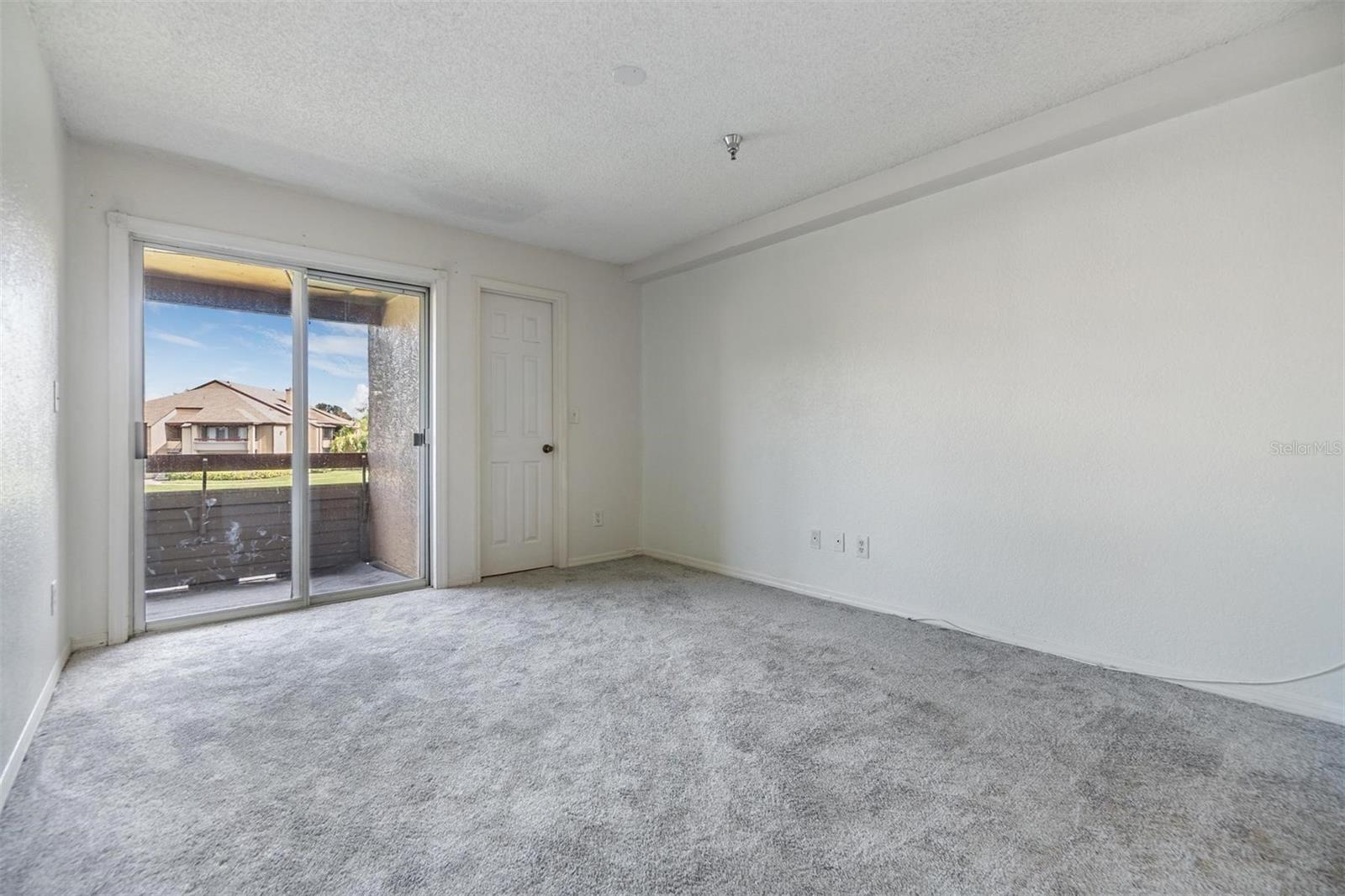 Main floor primary bedroom with sliders out to the second floor balcony to enjoy pond views and nature.