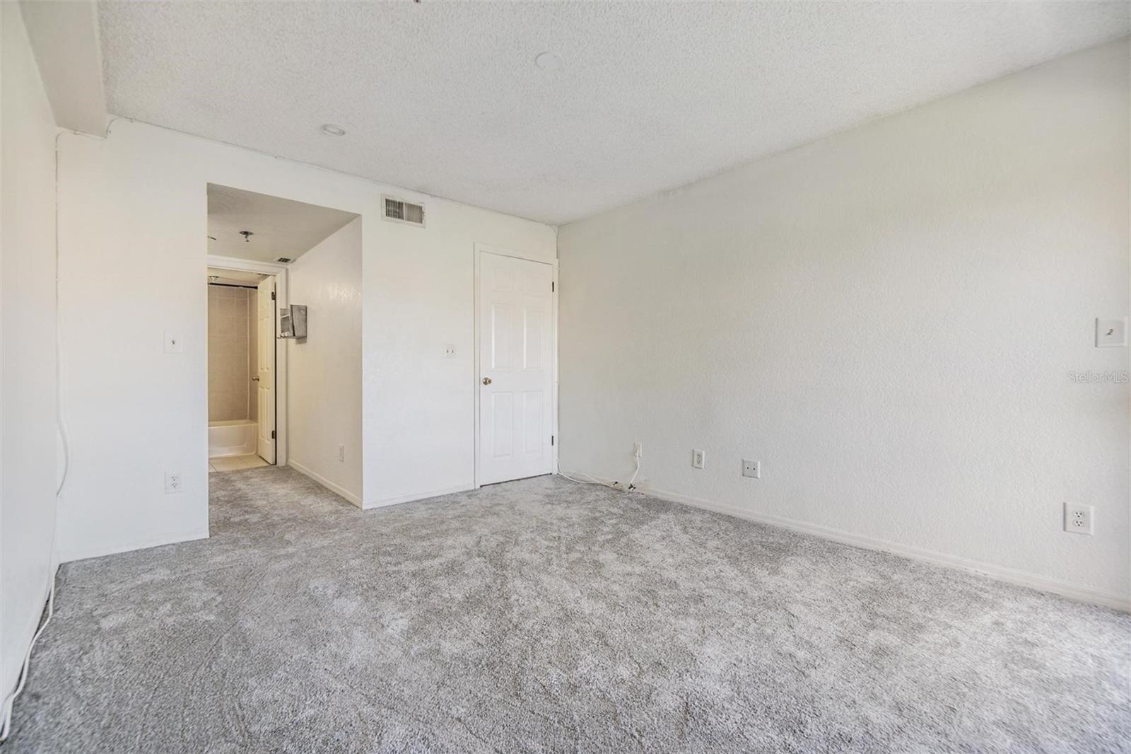 Main floor primary bedroom with ensuite bathroom and sliders out to balcony.