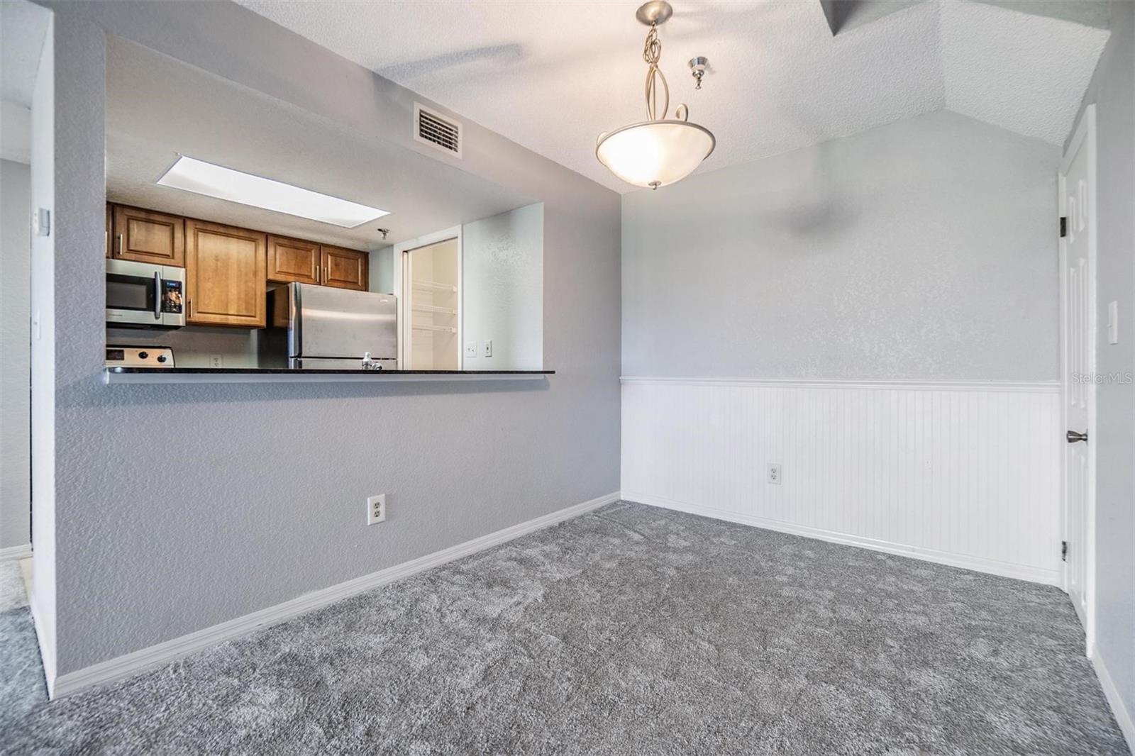 Kitchen overlooking dining area featuring decorative wainscoting on back wall.