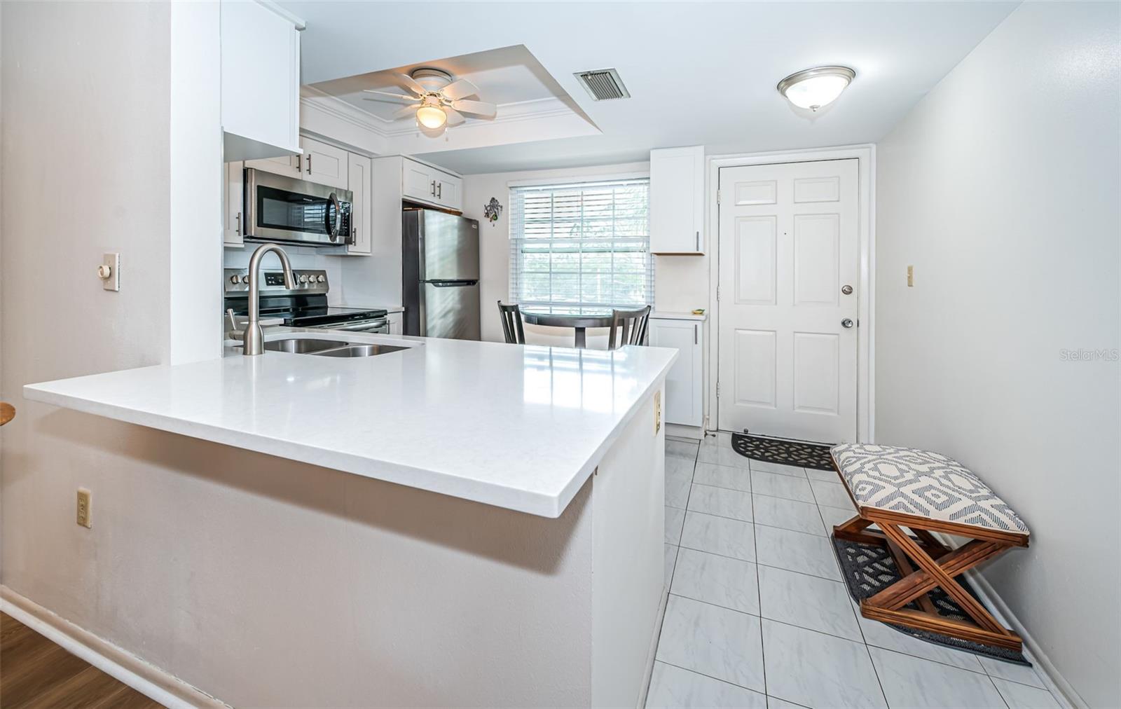 Tastefully remodeled Kitchen with:  White shaker cabinets and white quartz countertops, tray ceiling lighting with fan, stainless steel appliances, tiled flooring