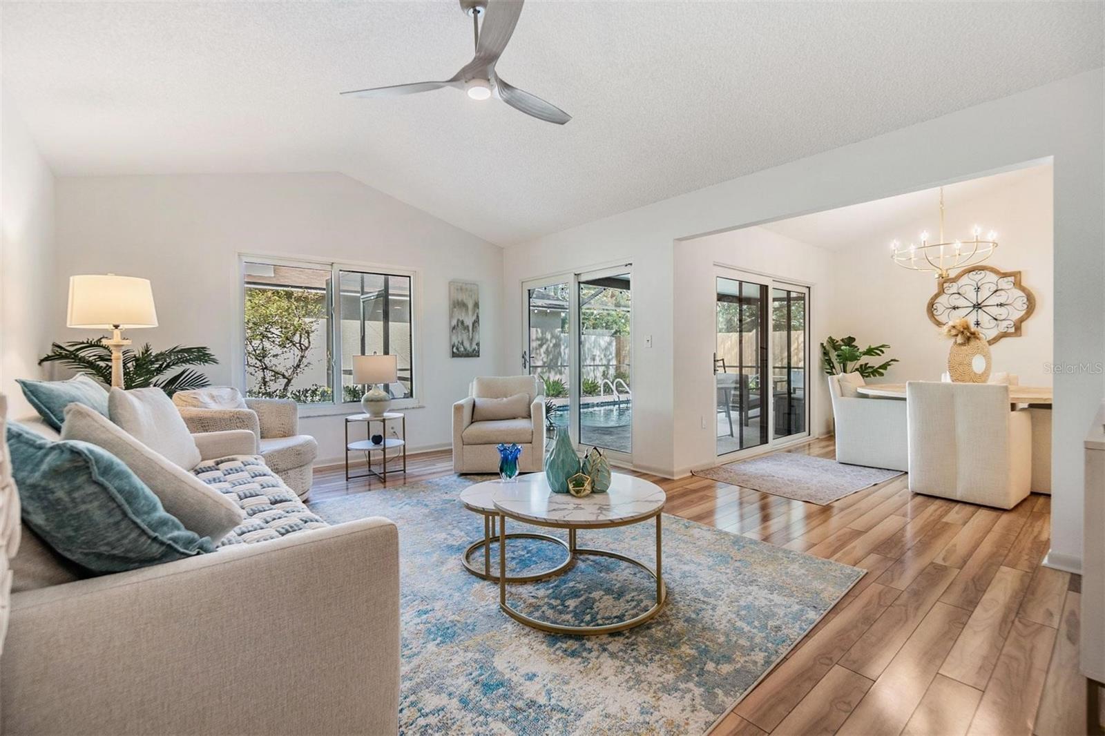 Enter through open living room with vaulted ceilings, beautiful floors, and many windows and sliders for a bright spacious and inviting atmosphere