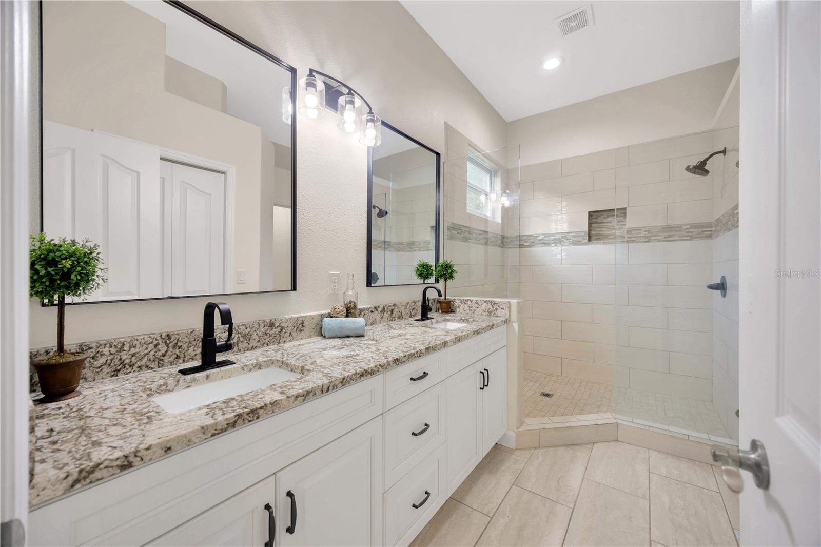 Primary bathroom with dual sinks, seamless glass shower, and walk in closet!