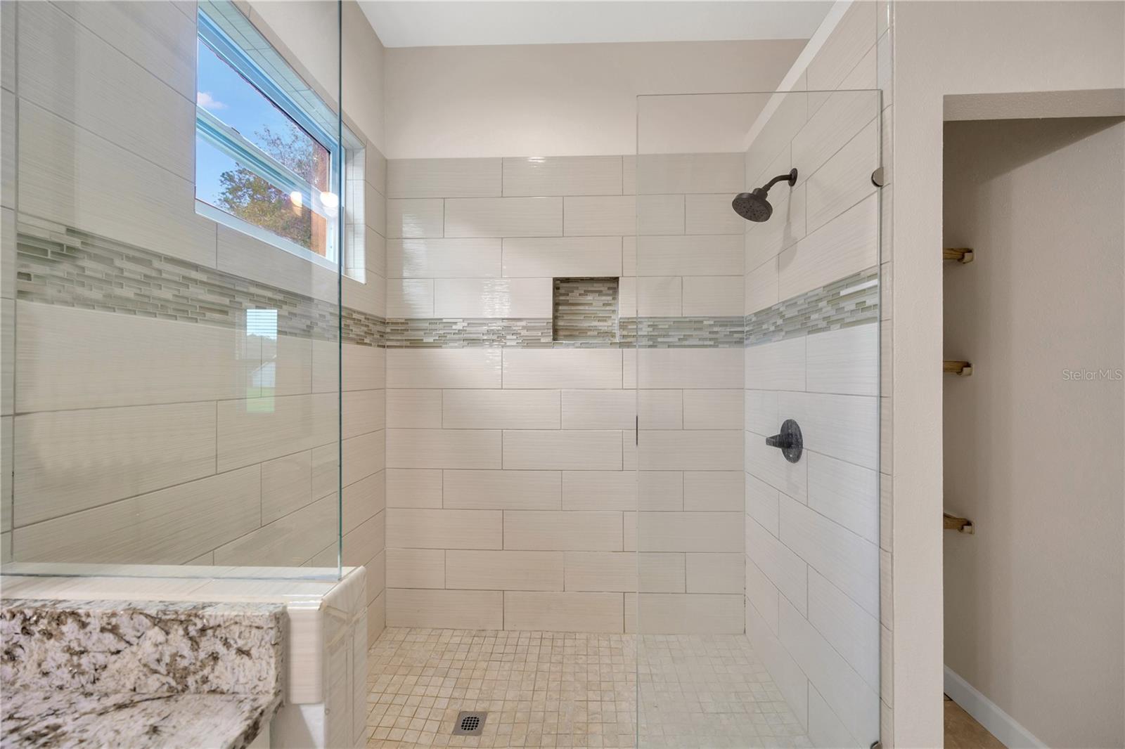 Primary bathroom with dual sinks, seamless glass shower, and walk in closet!