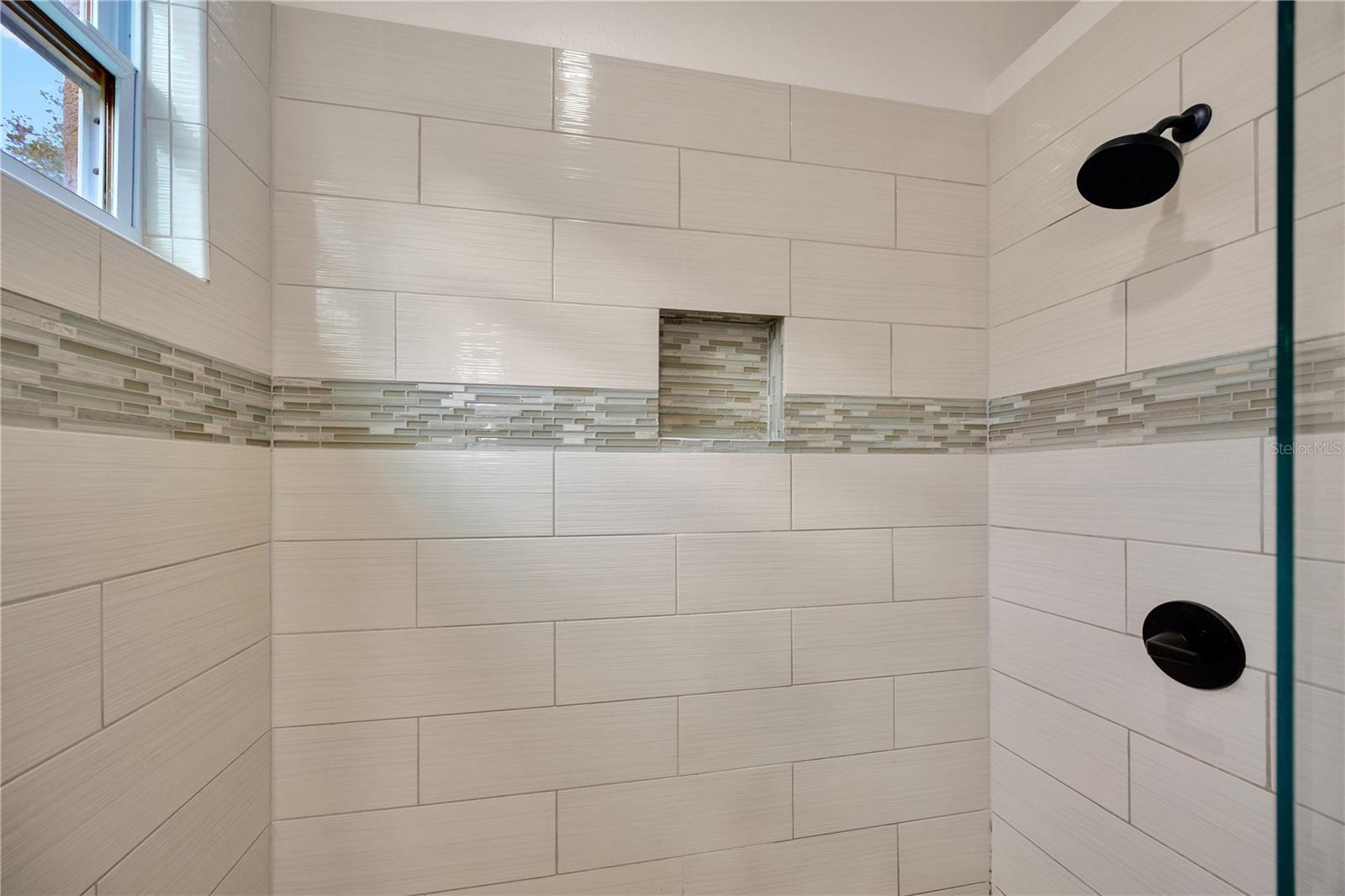 Primary bathroom with dual sinks, seamless glass shower, and walk in closet!