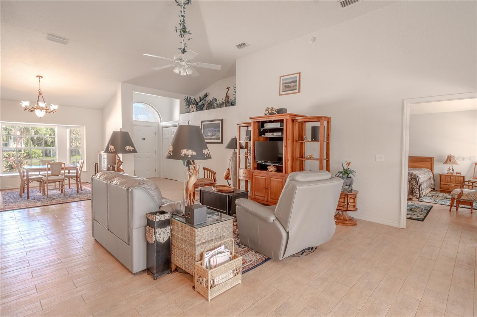 The living room features high ceilings, a ceiling fan with light kit and ceramic tile flooring.