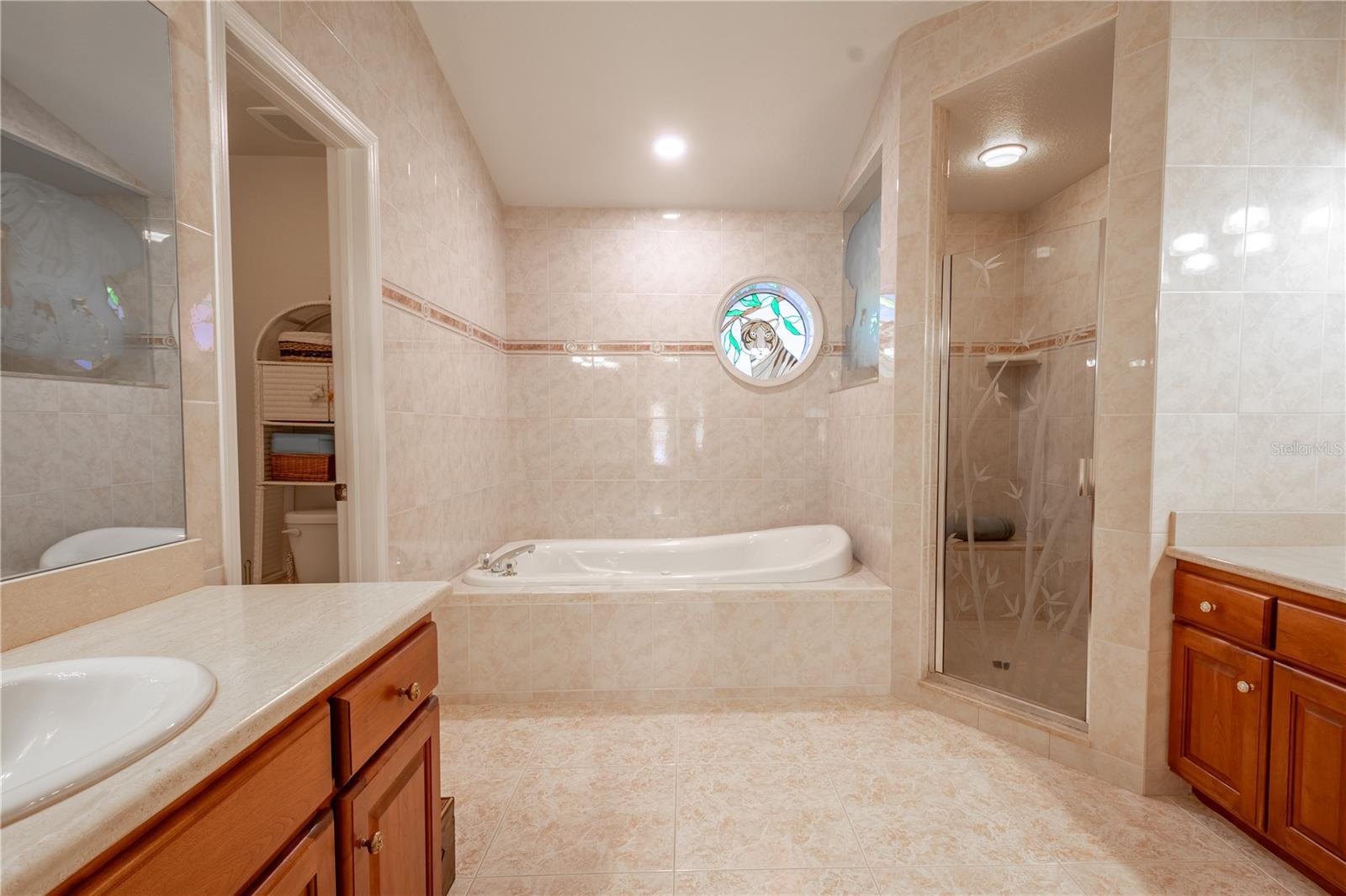 The primary bath features neutral tones, solid wood, mirrored his and hers vanities, a jetted tub and seperate walk-in shower.