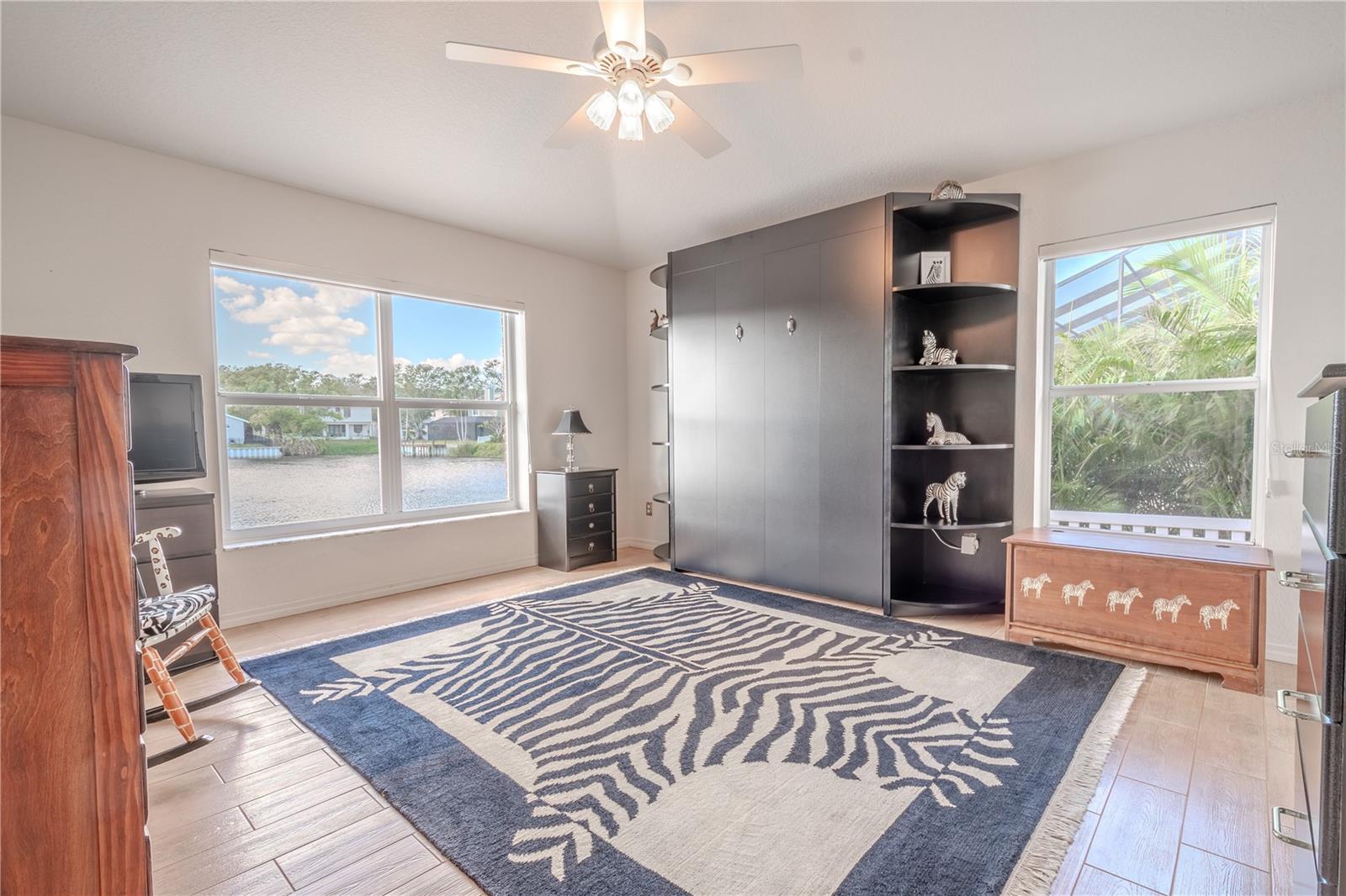 The 2nd bedroom features ceramic tile flooring, a serene water view, a ceiling fan with light kit, a built-in closet AND a Murphy Bed, ideal for a home office or guest bedroom.