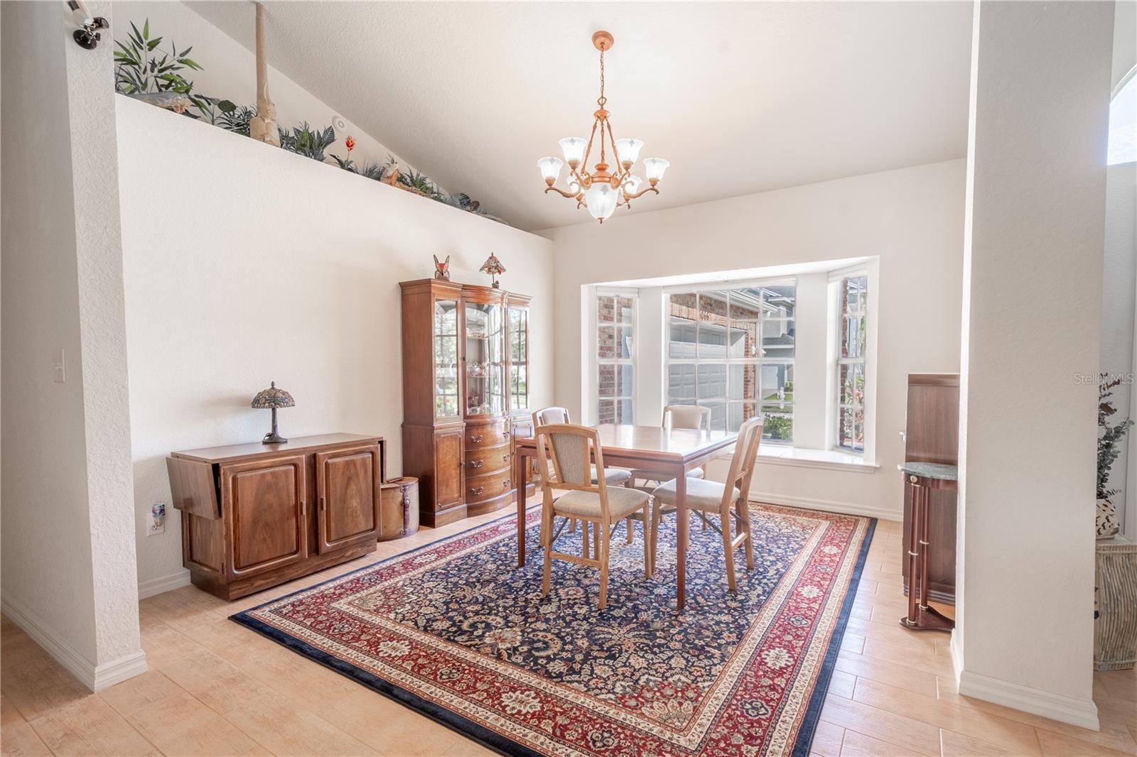 The dining room is framed by a large bay window and has a chandelier that illuminates your dining table.