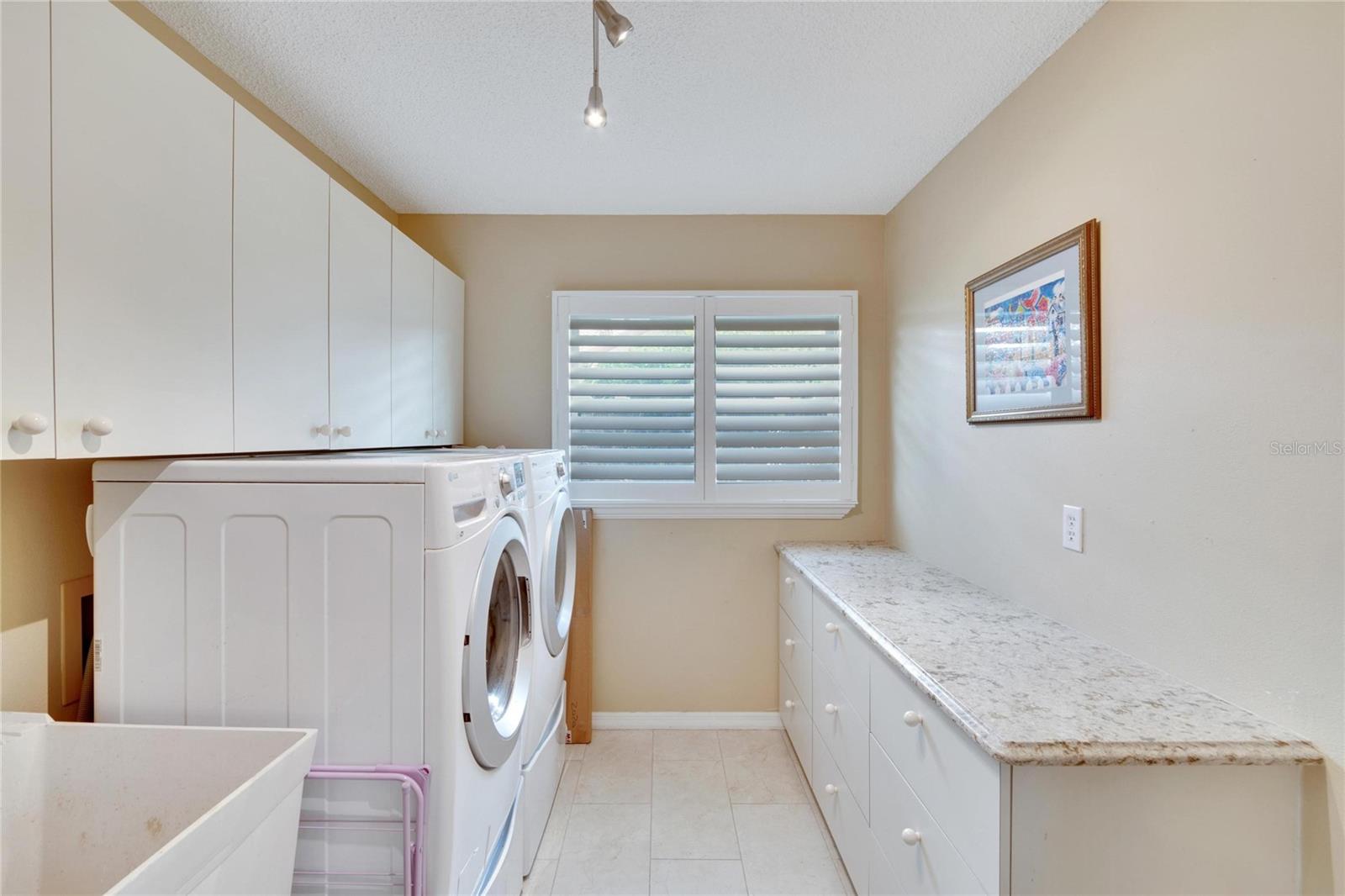 Interior Laundry with plentiful cabinetry, and long folding station/ craft area. measures 8x10 approximately.  Something you don't often see is a handy wash sink in the laundry room.  Do all your chores or crafts inside in the AC.  Laundry room is adjacent to the kitchen and leads to a two car garage.