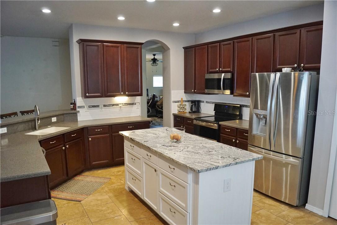 Large kitchen with stainless steel appliances, subway tile backsplash and an updated extra large island