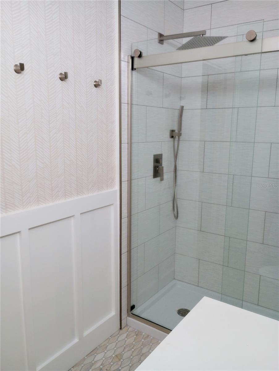 Ensuite bath features a walk-in shower with glass doors, rain shower head with a handheld sprayer and custom wainscoting.