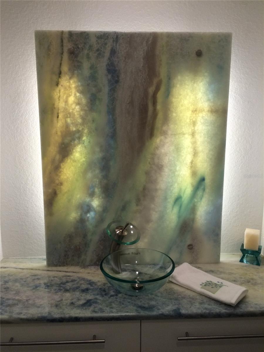 Hall Bathroom featuring a calcite countertop and custom lighted mirror wall panel.  The countertop, mirrored wall panel, sink and floating cabinet were preserved during the remediation.