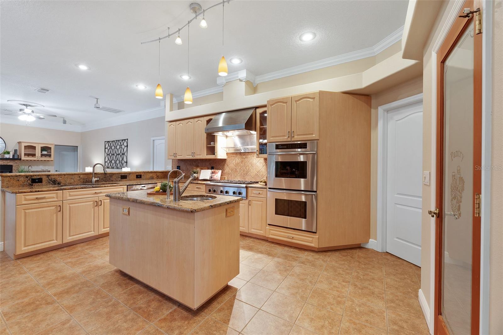 The kitchen boasts 2 sinks with disposals, a central kitchen island with a prep sink filtered through a reverse osmosis system, a spacious walk-in pantry, a breakfast bar for casual dining and elegant granite countertops.