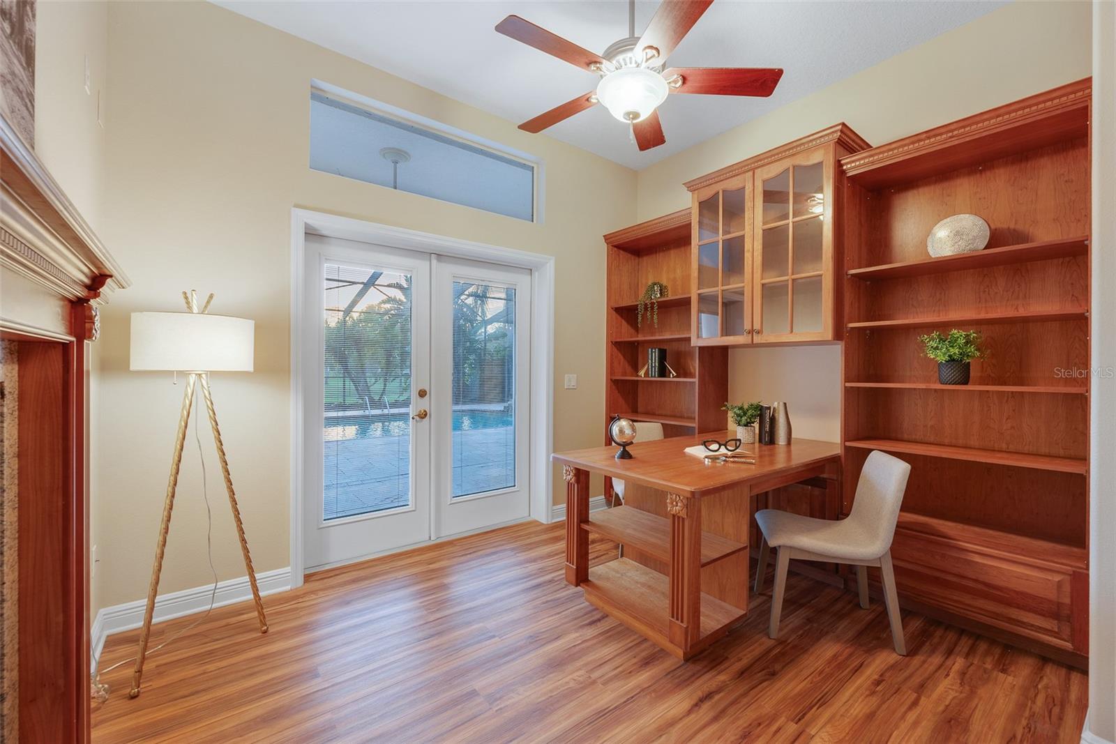 This secluded office/den features built-in shelving and double french doors leading outside to the pool.