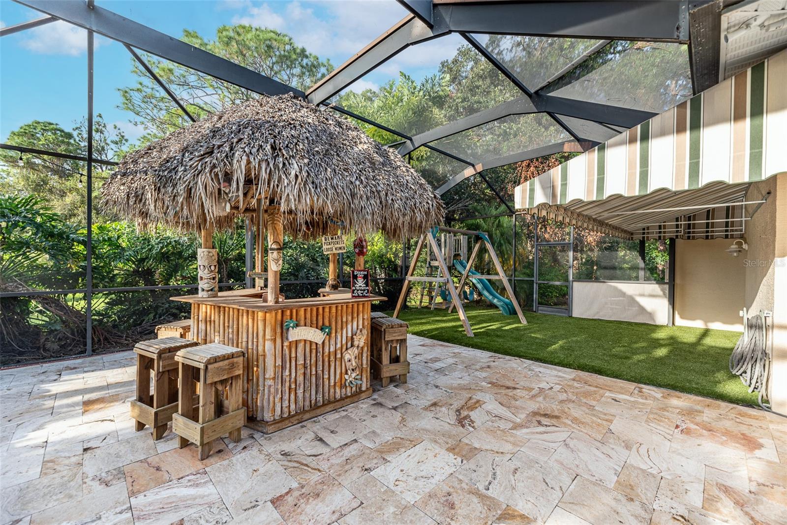 Check out this fun thatched Tiki bar with a fan & light for entertaining after sunset.  The youngsters will enjoy the safe play space tucked behind this home but still protected from the mosquitos within the screen.