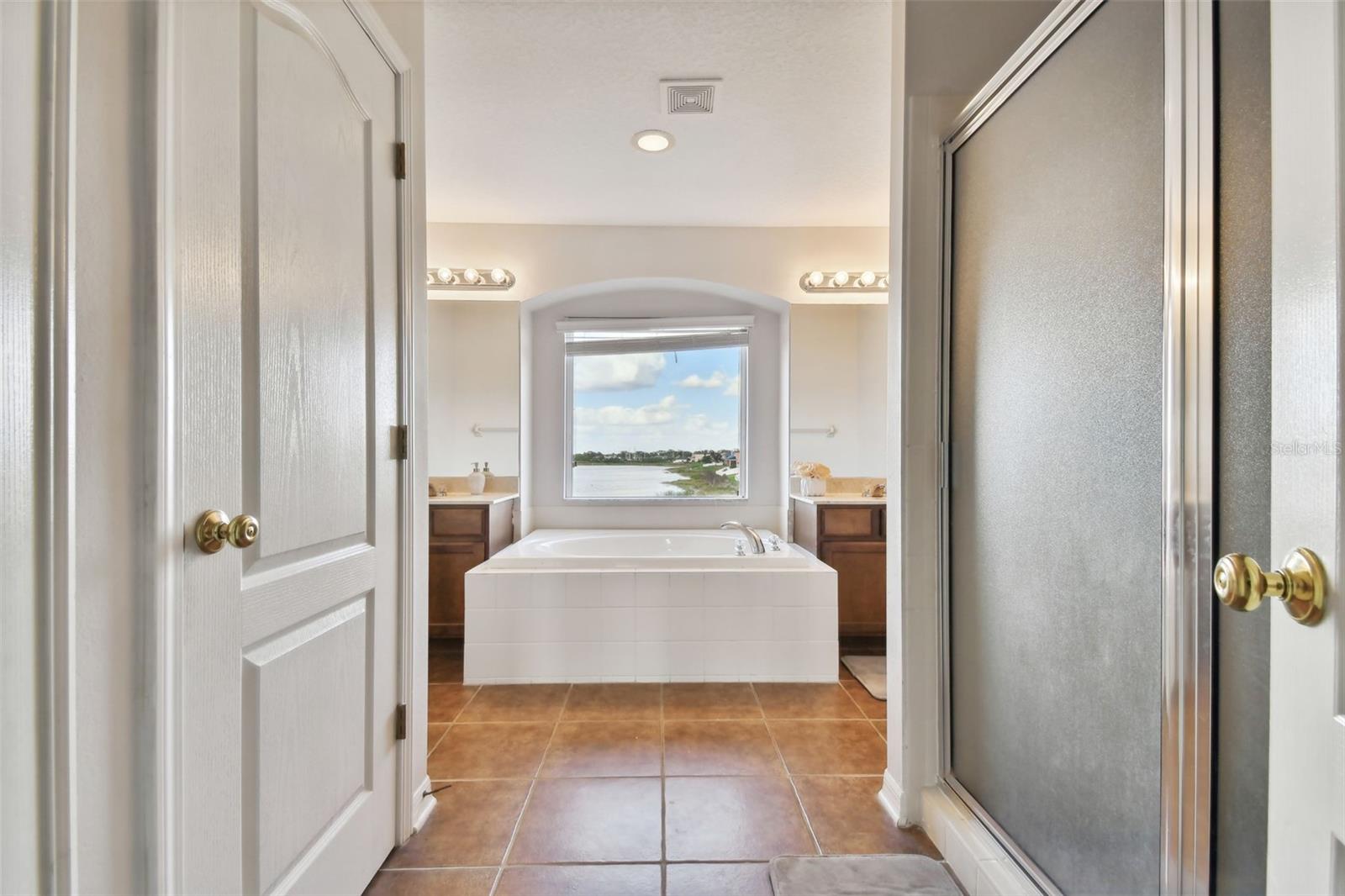 Entry to master bathroom with garden tub and separate glass enclosed shower . Private powder room and window with water view