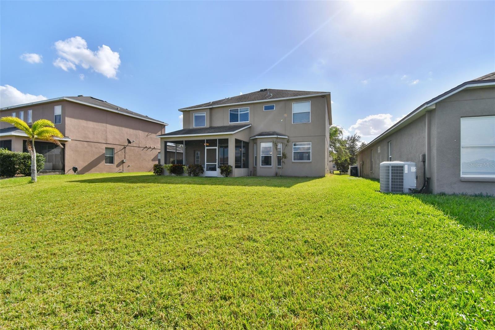 Back exterior with plenty room to put a pool fencing is allowed or paved outdoor lanai. The space and possibilities are endless.