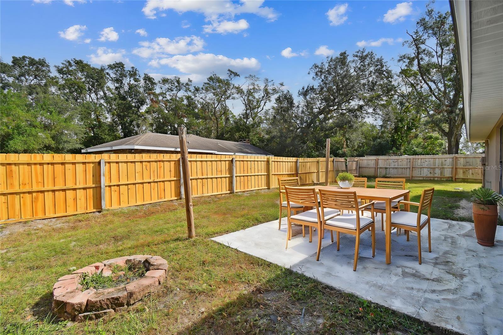 Large backyard with firepit and concrete pad for dining area