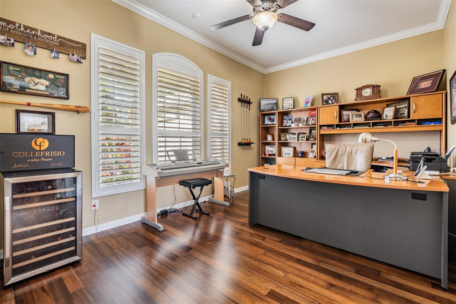 Office with Ceiling Fan/light fixture, Plantation Shutters, Crown Molding, Burma Walnut Flooring and French Doors.