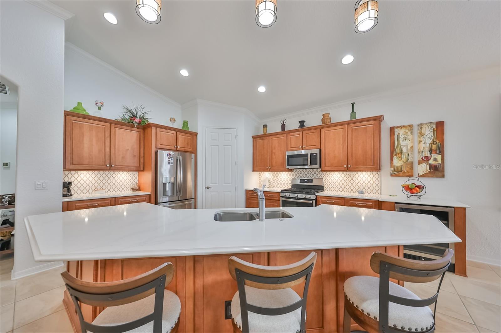 Beautiful all wood cabinets, travertine and fixtures lend a tropical feeling to the space. Quartz countertops provide an air of elegance, but easy maintenance