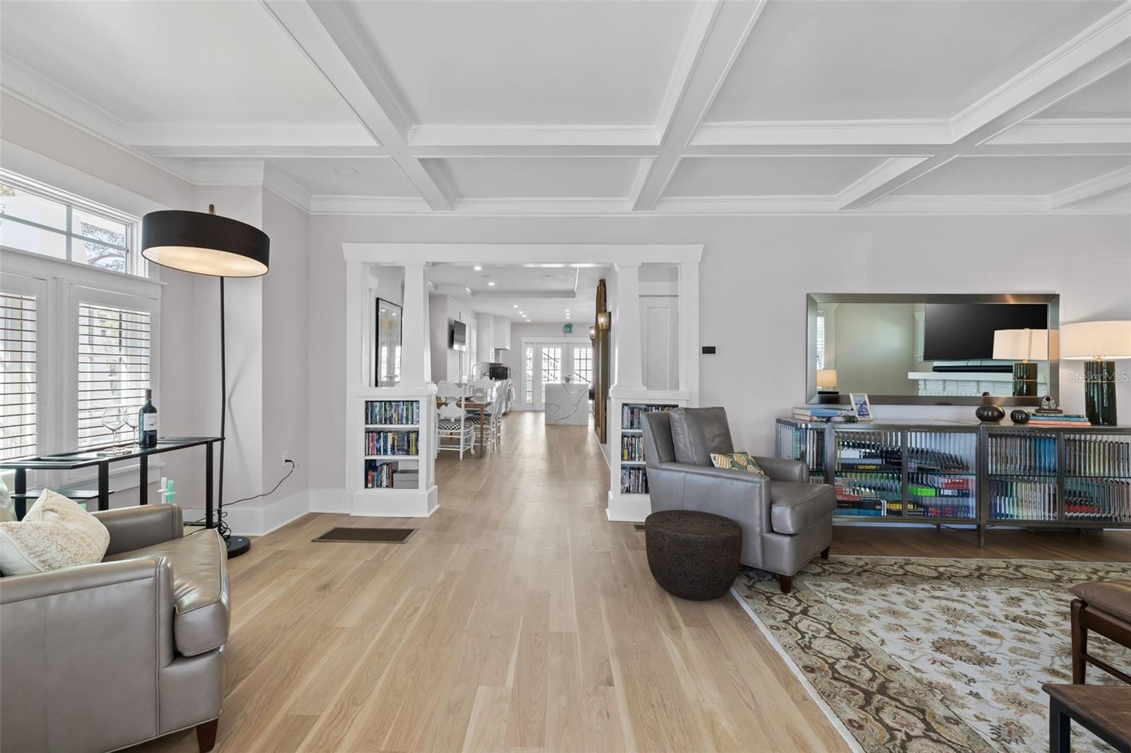 Living room opens through to dining and kitchen, divided by bookshelves and columns