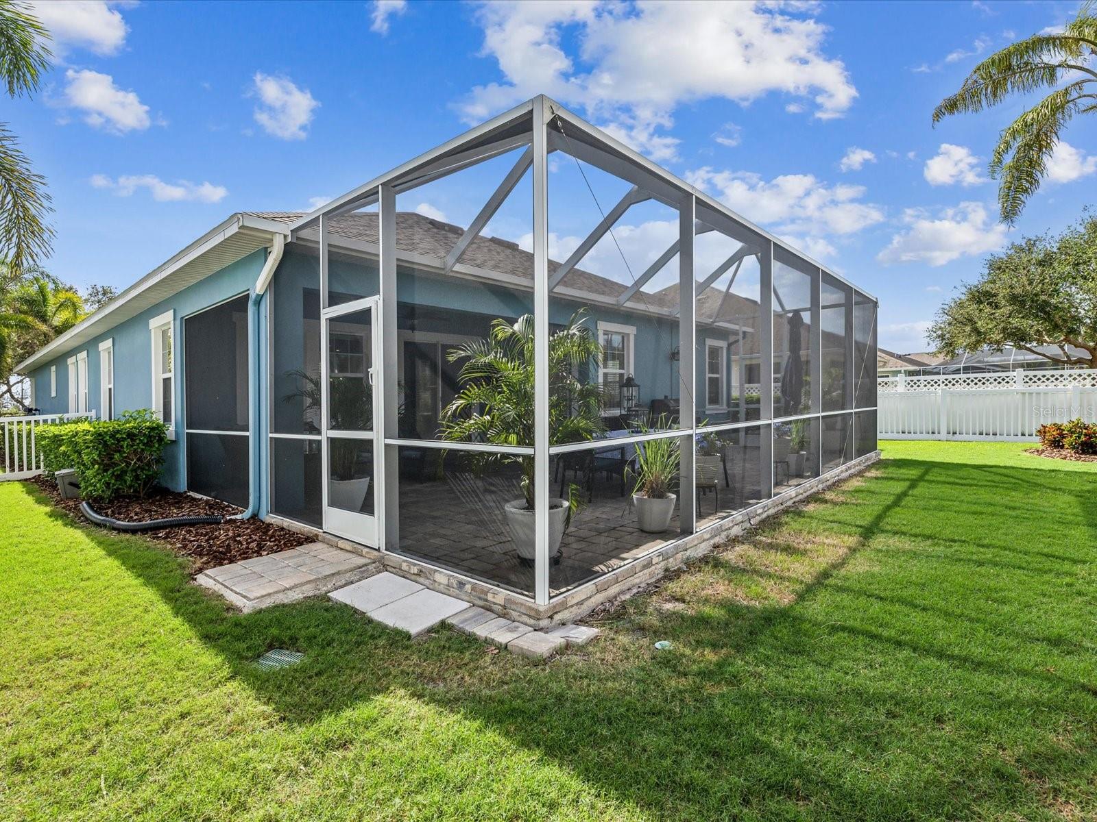 Exits on either side of the enclosed lanai lead to the manicured backyard and surrounding property.