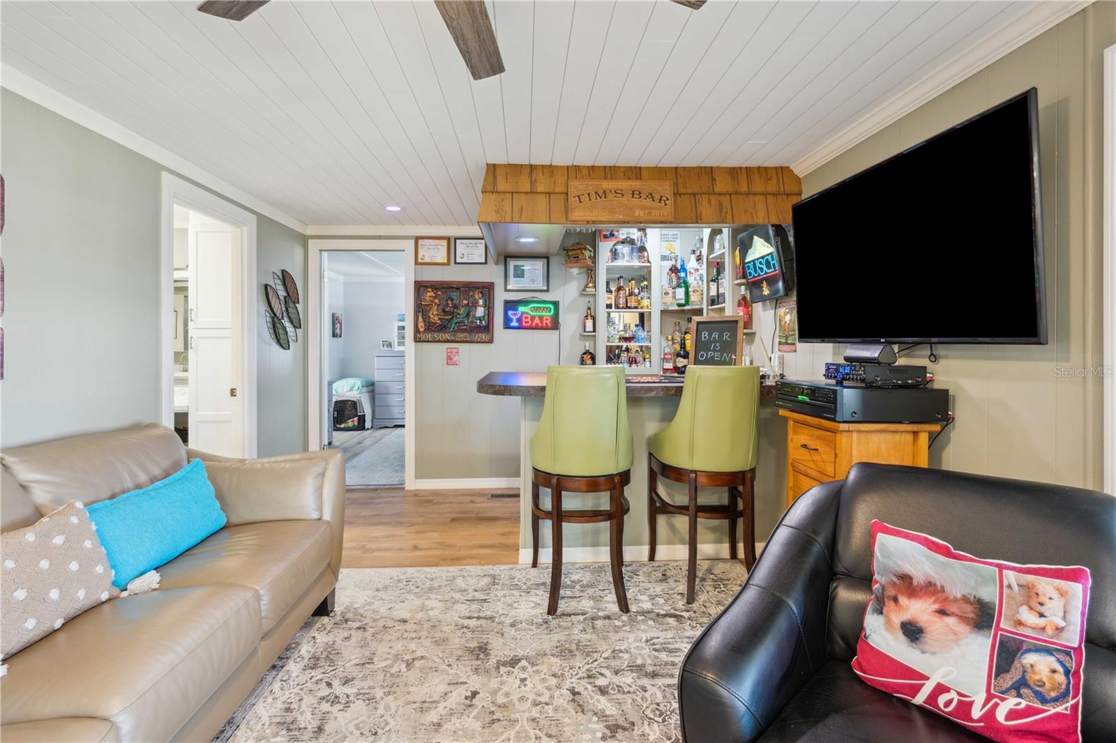 The family room is off kitchen with ceiling fan and wet bar.