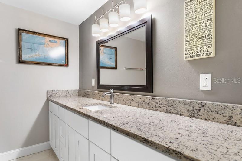 Renovated primary bathroom features granit counter tops, tub with shower.