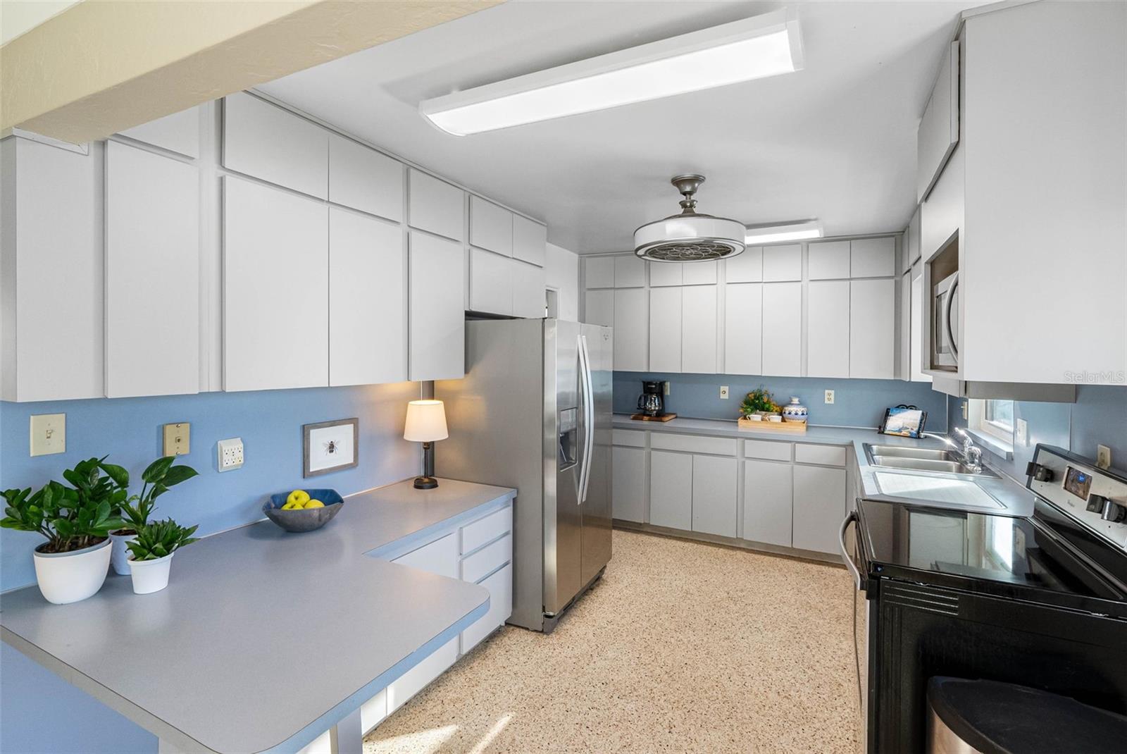 Stainless steel appliances and sleek gray cabinets offer a perfect blend of functionality and vintage charm.