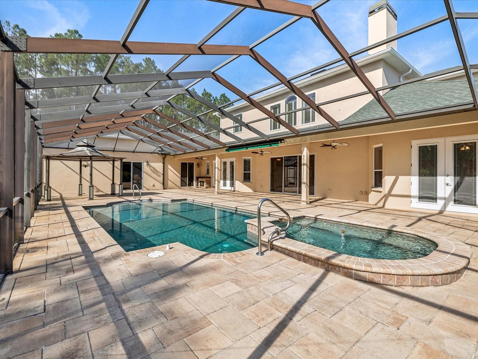 The lanai and pool area provide a private oasis, complete with a zero-entry pool, a rejuvenating spa tub, awning sunshade, & a pop-up self-cleaning feature. A gazebo within the screened enclosure includes a wet bar, refrigerator, making it the ultimate space for outdoor leisure & entertainment