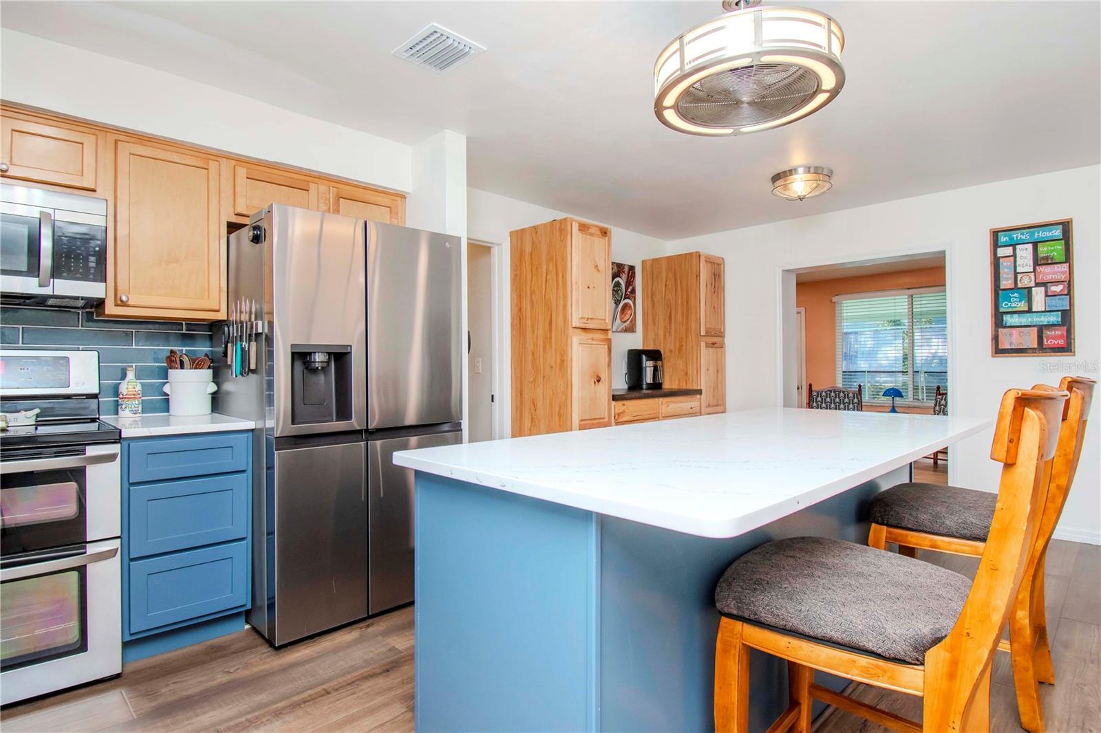 View of kitchen island, new stainless refrigerator and new wood cabinets.