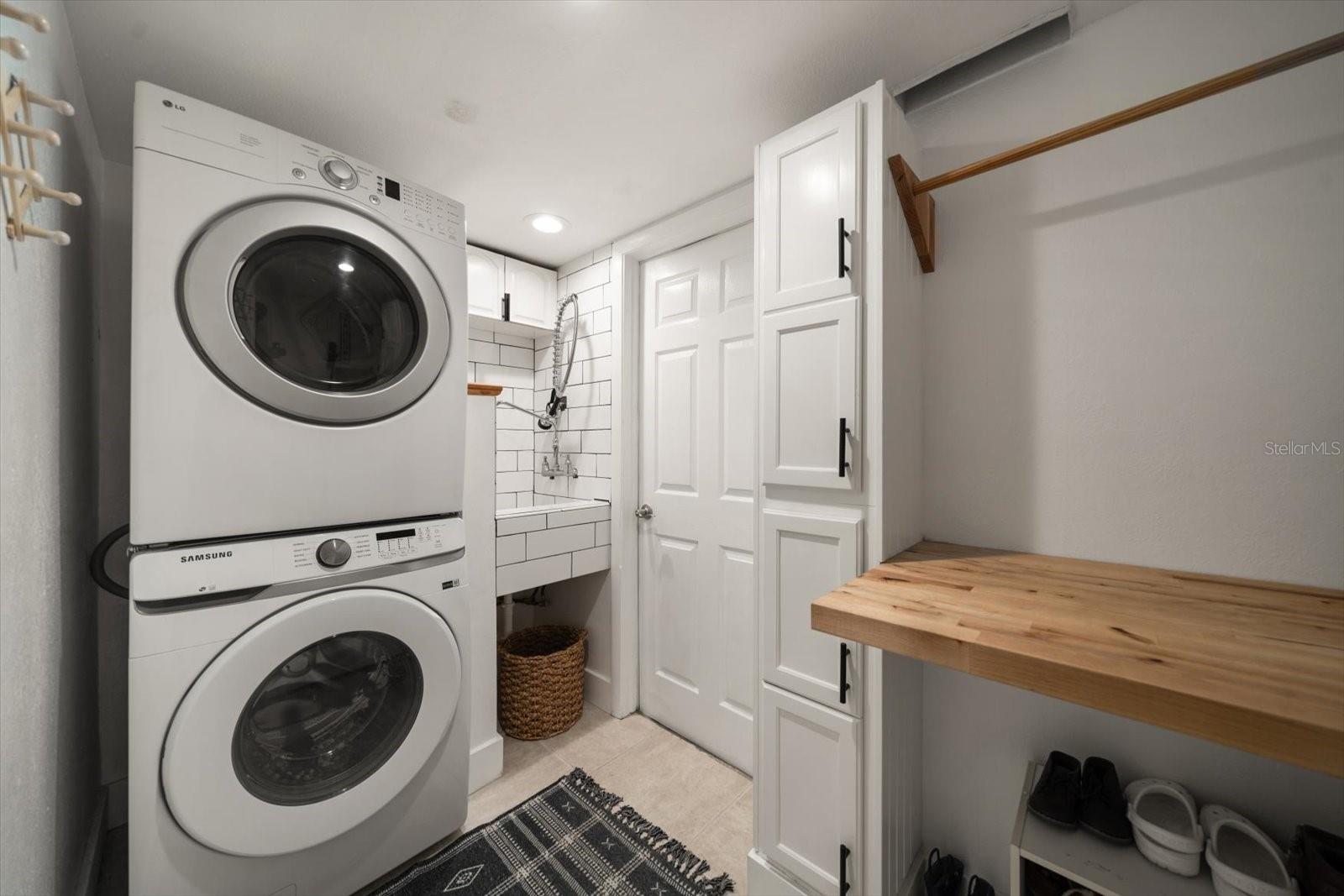 Inside laundry room with separate folding area and tiled  sink