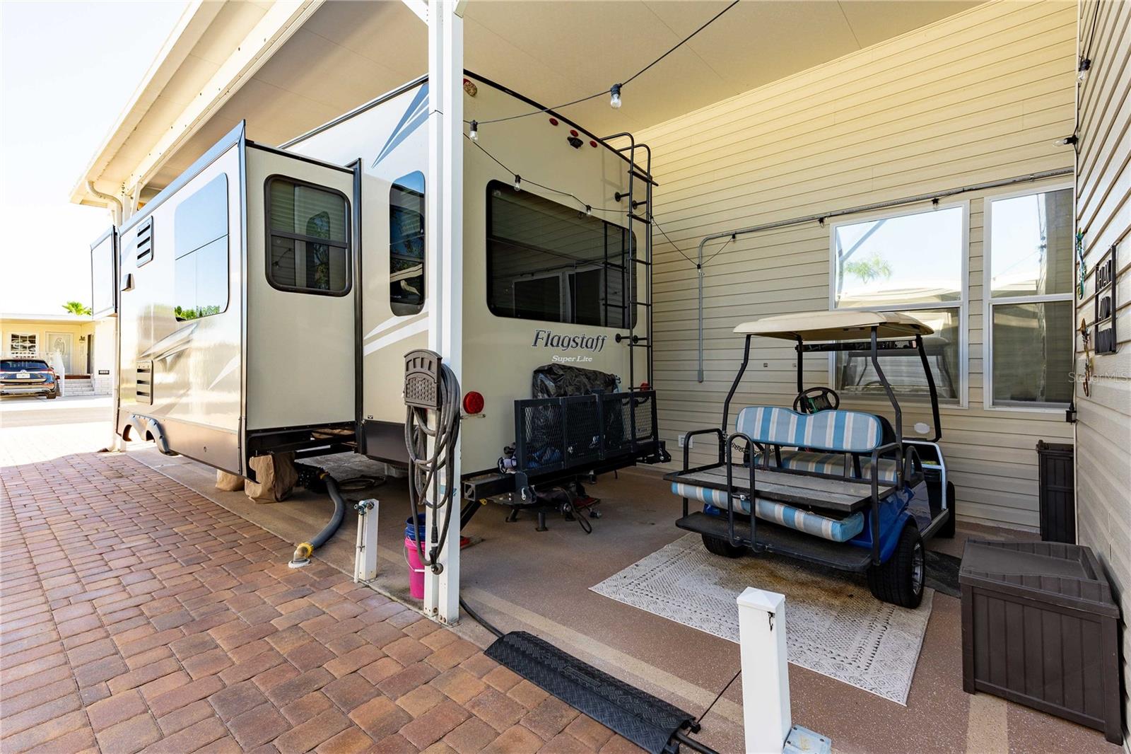 Golf cart parking area is near storage shed with washing/dryer facilities.