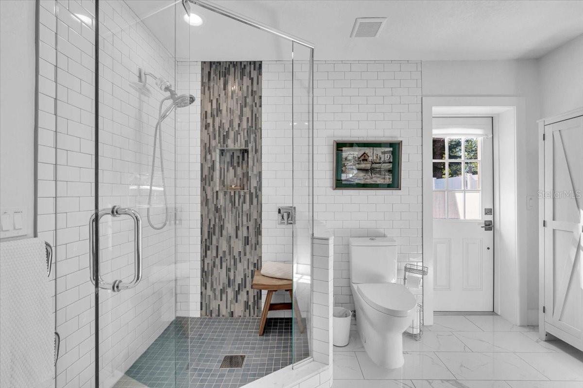 Large walk in shower, subway tiles to the ceiling, entrance out to the back yard and an outdoor shower.